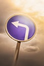 Turn left ahead sign, blue round roadside traffic signage, against the dramatic sky Royalty Free Stock Photo