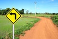 Turn left warning sign with soil road