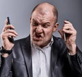 Turn nasty loud crying angry business man talking on two mobile phone very emotional in office suit on grey background. Closeup Royalty Free Stock Photo