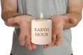 Turn off lights for Earth hour. Man holding burning candle on white background, closeup