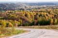 Turn of the road, leaving in the autumn Russian forest with colorful yellow, red and green trees a sunny day Royalty Free Stock Photo