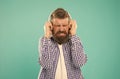 turn the sound down. unhappy hipster listening ebook. bearded man with loud sound in earphones.