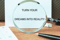 TURN YOUR DREAMS INTO REALITY words focused on the notebook through a magnifying glass Royalty Free Stock Photo
