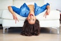 Turn your frown upside down. a young woman showing the peace sign while lying upside down on her sofa. Royalty Free Stock Photo