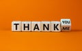 Turned a cube and changed the expression `thank you` to `thank me` or vice versa. Beautiful yellow table, orange background, c Royalty Free Stock Photo