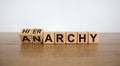 Turned a cube and changed the word `anarchy` to `hierarchy`. Beautiful wooden table, white background. Business concept. Copy