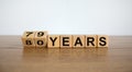 Turned cubes and changed the expression `79 years` to `80 years` or vice versa. Beautiful wooden table, white background. Busi