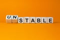 Turned cubes and changed the word `unstable` to `stable` or vice versa. Beautiful orange background. Business concept. Copy sp