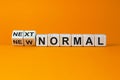 Turned cubes and changed the words `new normal` to `next normal`. Covid-19 postpandemic concept. Beautiful orange background, Royalty Free Stock Photo