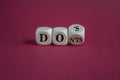 Turned cubes and changes the word don\'ts to does. Beautiful red background, copy space.