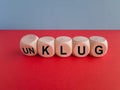 Turned dice and changes the German word unklug (stupid) to klug (smart). Beautiful red table, blue background