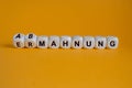 Turned dices and changes the German word Ermahnung to Abmahnung. Beautiful orange background. Royalty Free Stock Photo