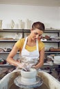 She turned her hobby into a career. a young woman making a ceramic pot in a workshop.