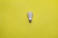 Turned off electric energy-saving lamp on a yellow background Royalty Free Stock Photo