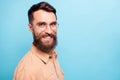 Turned photo of charming man looking with beaming smile wearing brown shirt over blue background