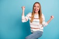 Turned photo of cheerful trendy white woman smiling toothily rejoicing in having won lottery making fists wearing jeans Royalty Free Stock Photo