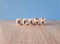 Turned a wooden cube and changes the German word spass to sparen . Beautiful wooden table blue background.