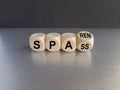 Turned a wooden cube and changes the German word spass to sparen. Beautiful grey table black background. Symbol for saving money
