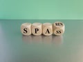 Turned a wooden cube and changes the German word spass to sparen. Beautiful grey table blue background. Symbol for saving money