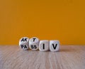 Turned wooden cubes and changes the German word passiv to aktiv. Beautiful wooden table orange background.