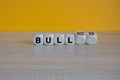 Turned wooden cubes and changes red word Bull to Bulldozed. Beautiful wooden table orange background. Business bull or bulldozed