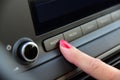 Turning on the car radio. A woman`s finger on the button to turn on the car radio.