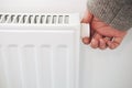 Turning down thermostat of a central heating radiator. Energy saving, cold winter season, reduced power consumption and economy Royalty Free Stock Photo