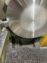 turning of a large steel disc seen from the front, with the cutting tool and some metal chips