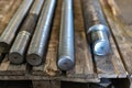 After turning and milling, the threaded studs lie on a wooden rack in the warehouse