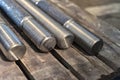 After turning and milling, the threaded studs lie on a wooden rack in the warehouse