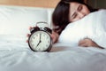 Turning off Sound or Snoozing The Alarm Clock Concept, Beautiful Woman Waking Up in The Morning at Bedroom While Her Hand is Royalty Free Stock Photo