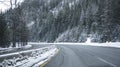 Turning winding divided highway road at winter dangerous condition with snow and ice and mountain with forest in Montana