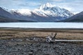 Turquoise Alaskan lake with snow capped mountains as a backdrop.