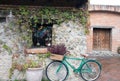 Turquoise bicycle lying against a stone brick wall