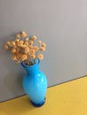 Turquoise blue bright glass bud vase flowers dried brown country bouquet on yellow shelf with gray background Royalty Free Stock Photo