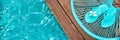 Turquoise blue garden chair and flip flops on the edge of a swimming pool Royalty Free Stock Photo