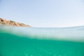 Turquoise blue sea above water surface and underwater. Sun glare at the bottom of ocean. Waves underwater and rays of sunlight