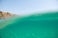 Turquoise blue sea above water surface and underwater. Sun glare at the bottom of ocean. Waves underwater and rays of sunlight