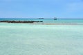 Turquoise blue sea water on a lagoon with a ship on a horizon line ander a cloudy sky. Royalty Free Stock Photo