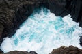 Turquoise blue water cave pit hole with splash rough seas Royalty Free Stock Photo
