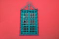 Turquoise blue wrought iron window on vibrant red concrete wall