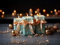 Turquoise burning candles with gold ribbons and and gold orbs stand on a light colored wooden stand on a dark background with Royalty Free Stock Photo