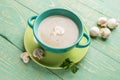 Turquoise ceramic bowl with mushroom cream soup on green plate on diagonal green wooden background