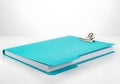 Turquoise clipboard with a stack of white paper on a white surface Royalty Free Stock Photo