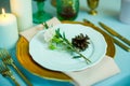 Turquoise-colored table with gold plates and cutlery. top view