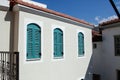 Turquoise colored window shutters on a white house. Wooden windows with closed shutters. Shutters on the windows protect Royalty Free Stock Photo