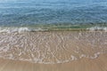 Turquoise foamy wave on a golden sandy shore. The calm surface of the sea. Relax and tranquility. Background. Space for text