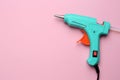 Turquoise glue gun with stick on pink background, top view. Space for text Royalty Free Stock Photo