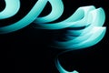 Turquoise green glow neon wave line of light as curls or swirl with smooth stripes on black background, pattern Royalty Free Stock Photo
