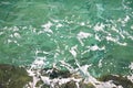 Turquoise green seawater with sea foam as background, close up. Surface of sea with waves, splash, foam and bubbles. Royalty Free Stock Photo